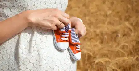 chaussures rouges de bébé sur ventre de femme enceinte