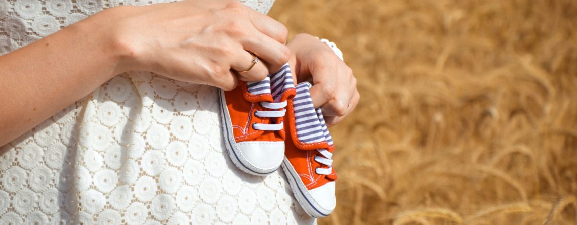 chaussures rouges de bébé sur ventre de femme enceinte