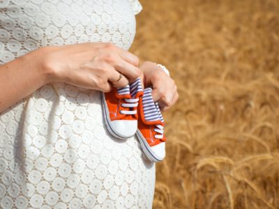 chaussures rouges de bébé sur ventre de femme enceinte