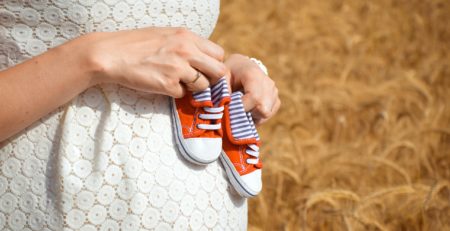 chaussures rouges de bébé sur ventre de femme enceinte