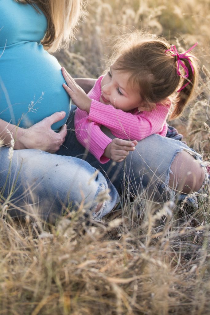 enfant qui touche le ventre de sa maman enceinte