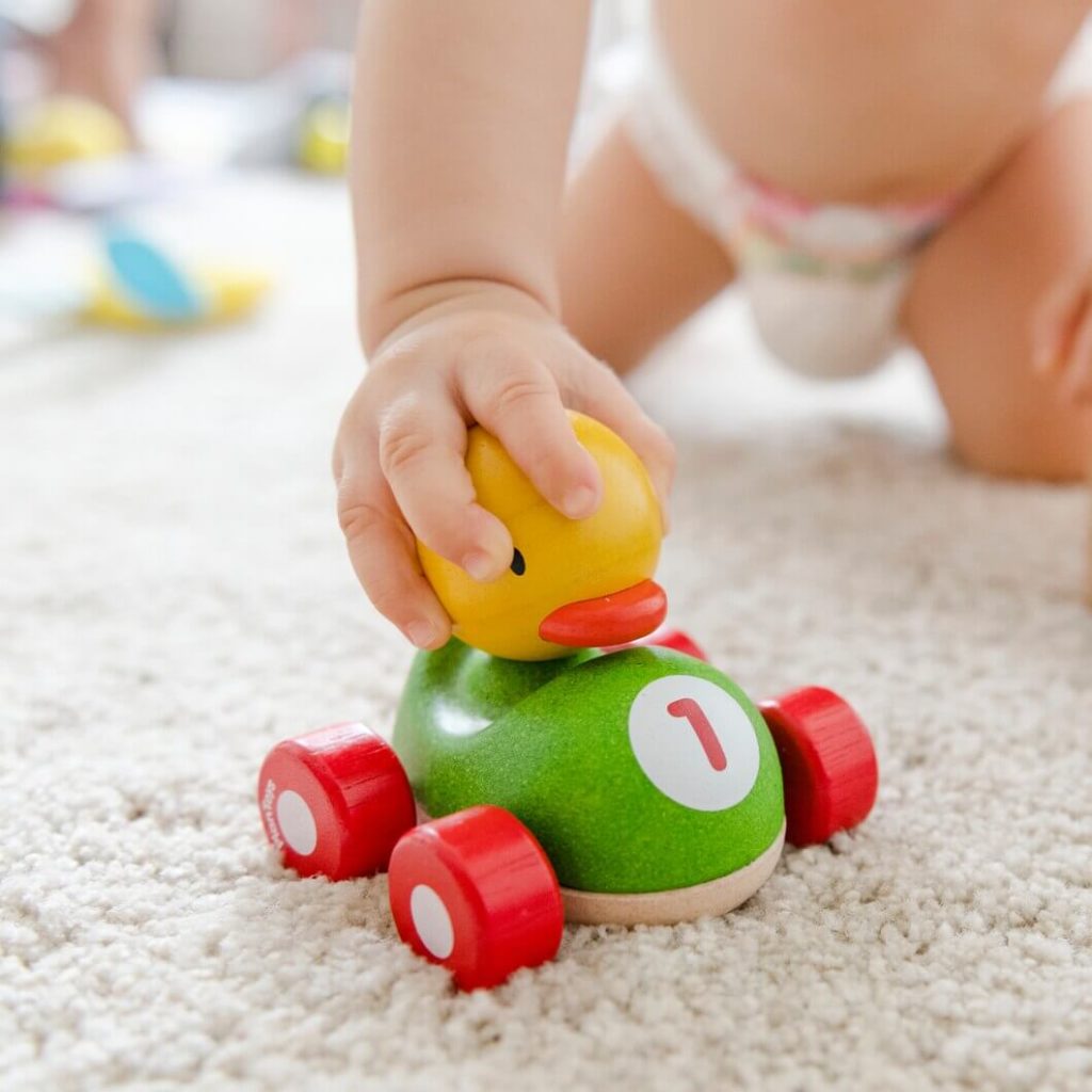 bébé joue avec une voiture en bois