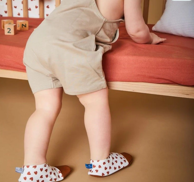 achats inutiles bébé chaussons petits pas enfant qui tient debout avec des chaussons aux pieds